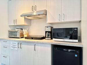 a kitchen with white cabinets and a microwave oven at Lakeside Getaway #4 - Spa - Sauna - Firepit in Sainte Brigitte de Laval +46 photos