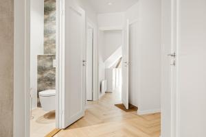 a bathroom with a toilet and a hallway with white walls at Bergen City Living in Bergen +12 photos