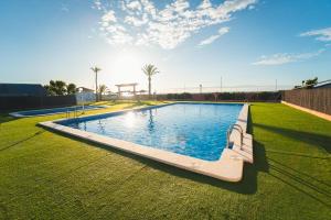 a large swimming pool with a bench in a grass field at Tres Estrellas Mediterráneo in Xilxes