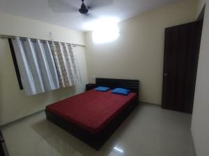 una camera con letto rosso e cuscini blu di 2 Bhk Luxury Apartment At Ovale Ghodbunder Road Thane West a Kolshet Altre 8 foto