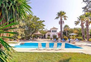 una villa con piscina y palmeras en Casa Rural Santa Ana, en Marchena