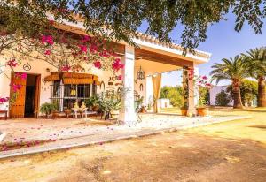una casa con flores rosas a un lado. en Casa Rural Santa Ana, en Marchena