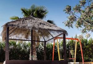 a playground with a straw umbrella and a swing at Casa Rural Villa Lucrecia in La Lantejuela