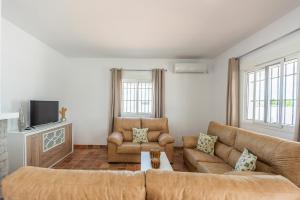 ein Wohnzimmer mit zwei Sofas und einem Fernseher in der Unterkunft Casa Brisa del Valle in Sevilla
