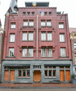 ein altes rotes Backsteingebäude mit orangefarbenen Türen in der Unterkunft The Bank Hotel in Amsterdam