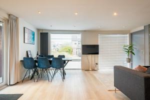 Una sala de estar con una mesa de comedor con sillas azules. en Wasser - Modern Beach house, en Bergen aan Zee