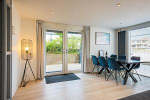 Un comedor con una mesa y sillas azules. en Wasser - Modern Beach house, en Bergen aan Zee