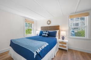 a bedroom with a blue bed and two windows at Marina Bay Cottages in Waterford