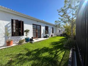 a white house with a yard with green grass at Helder Haven Cottage in Somerset West