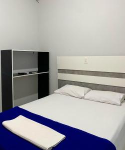 a bedroom with a bed with a blue blanket on it at Hotel Veneza in Garanhuns