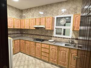 a kitchen with wooden cabinets and a sink at Al Murooj Hotel Apartments in Muscat