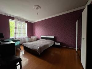 a bedroom with a bed and a purple wall at Maia's Farmstay in Dedoplis Tskaro +117 photos