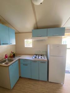 a kitchen with blue cabinets and a white refrigerator at Camping Internazionale Di Castelfusano in Lido di Ostia