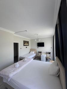 a white bedroom with two beds and a tv at Ali's Pension ada alis in Egirdir