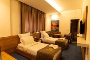 una camera d'albergo con due letti e una televisione di Mateus Hotel & Pool a Jounieh