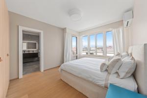 a white bedroom with a large bed and a window at Exclusive 3 Bedroom Luxury penthouse in Geneva