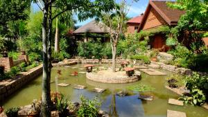 a garden with a pond in front of a house at Eco Lodge Les Chambres Du Voyageur in Antsirabe