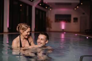 a man and woman swimming in a swimming pool at FAVORITE Parkhotel I Spa - Business - Fine Dining in Mainz