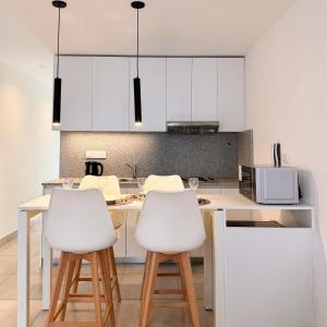 a kitchen with white cabinets and white stools at Rossi Tiny in Villa Mercedes
