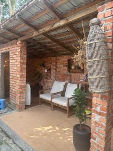 a patio with a couch and a chair under a brick wall at Lelangit Inn in Port Dickson