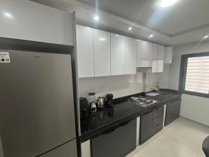 a kitchen with white cabinets and a black counter top at appartement agadir in Agadir +65 photos