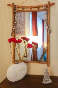 a vase with red flowers in front of a mirror at Suite ZEN 32m2 Centre ville Spa & Table massage &Parking in Amiens
