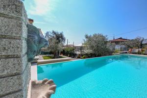 a swimming pool with a statue next to a wall at Villa Emma in Toscolano Maderno