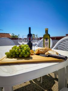 a wooden cutting board with grapes and wine bottles at Villa Terraca in Mandre