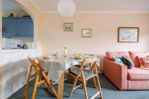 a dining room with a table and chairs and a couch at Anchorage - Quaint and Cosy Two-Bedroom House in Poole