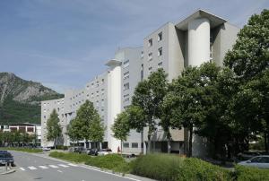 un edificio blanco con árboles frente a una calle en Séjours & Affaires Grenoble Marie Curie, en Grenoble