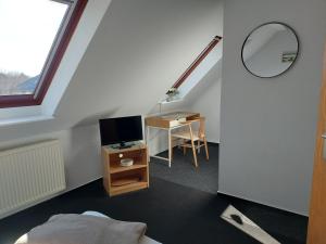 a bedroom with a bed and a desk with a television at Zur Eiche - Pension in Böhlen