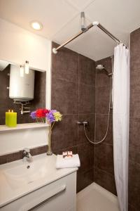 La salle de bains est pourvue d'une douche et d'un lavabo avec des fleurs sur un comptoir. dans l'établissement Séjours & Affaires Grenoble Marie Curie, à Grenoble