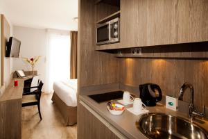 una cucina con lavandino e una camera con letto di Séjours & Affaires Grenoble Marie Curie a Grenoble