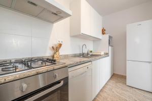 eine Küche mit weißen Schränken, einer Spüle und einem Kühlschrank in der Unterkunft Casa Teresa Deltebre in Deltebre + 19 Fotos