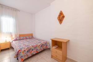 ein Schlafzimmer mit einem Bett und einem Nachttisch sowie einem Bett und einem Tisch in der Unterkunft Casa Teresa Deltebre in Deltebre