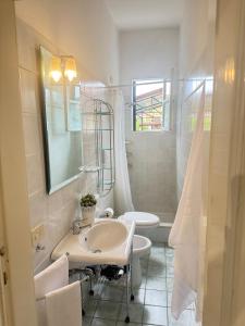 une salle de bain blanche avec un lavabo et un miroir dans l'établissement 50mt from sea Villetta White 2 bedr outdoor, à Marina di Pietrasanta