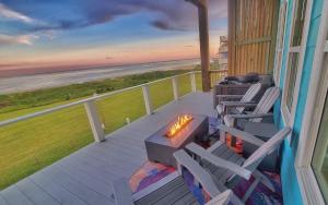 a deck with chairs and a fire pit on a beach at Beachfront - Hot Tub - Home Theater in Bolivar Peninsula