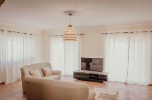 a living room with a couch and a tv at Casa dos Almargens - Moradia 3 quartos com piscina in São Brás de Alportel