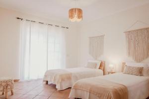 a bedroom with two beds and a chandelier at Casa dos Almargens - Moradia 3 quartos com piscina in São Brás de Alportel +10 photos