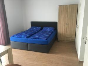 1 dormitorio con 1 cama con sábanas azules y armario de madera en Grefenstein, en Ettenheim