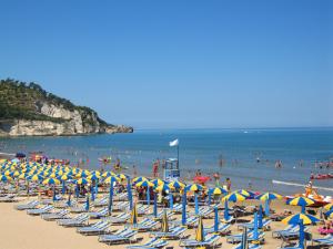 a beach filled with lots of chairs and umbrellas at Villaggio Bellariva in Peschici +14 photos