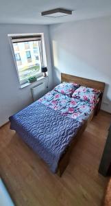 a bedroom with a bed with a blue comforter and a window at Apartament "Cztery Pory Roku" in Świdnik
