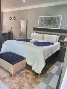 a bedroom with a large white bed with a blue blanket at No6 Myburgh Bed & Breakfast in Klerksdorp +11 photos