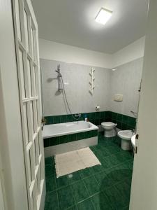a green bathroom with a tub and a toilet at Jungle Rooms in Cetara