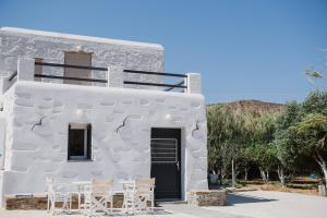 a white building with white chairs and a black door at Aloni Houses Kythnos in Loutra