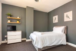 a bedroom with a white bed and a tv at Spacious 4 Bedroom House with Garden in Doncaster in Doncaster