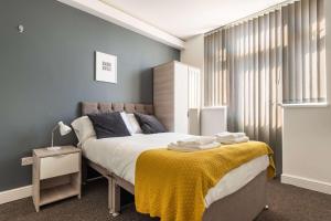 a bedroom with a bed with a yellow blanket on it at Spacious 4 Bedroom House with Garden in Doncaster in Doncaster