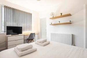 a white room with a bed with two towels at Spacious 4 Bedroom House with Garden in Doncaster in Doncaster