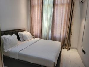 Wintana Apartments Kigali في كيغالي: سرير مع ملاءات ووسائد بيضاء في غرفة النوم