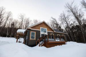 a house with a deck in the snow at Dreamy Artist Chalet in Secluded Historic Village in Warren